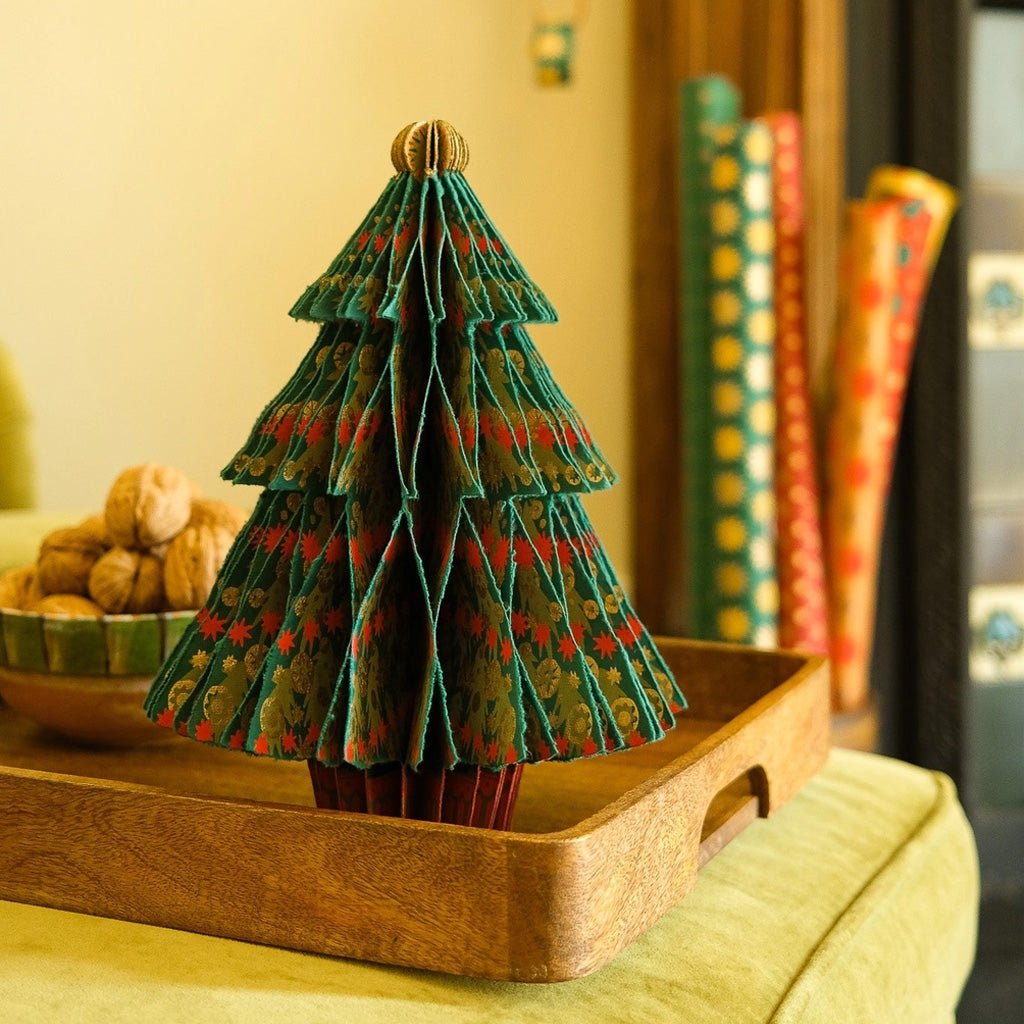A decorative paper Christmas tree on wooden tray.