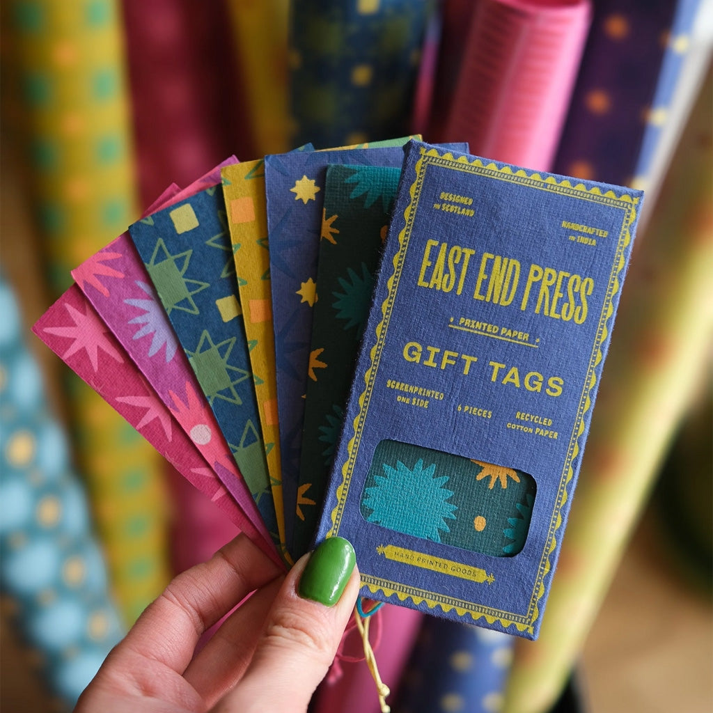 Hand holding colorful gift tags and blue box.