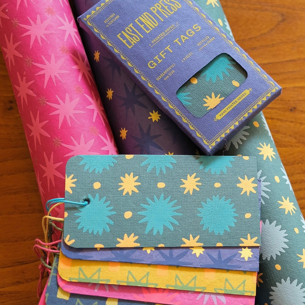 Colorful gift tags on top of rolls of wrapping paper.