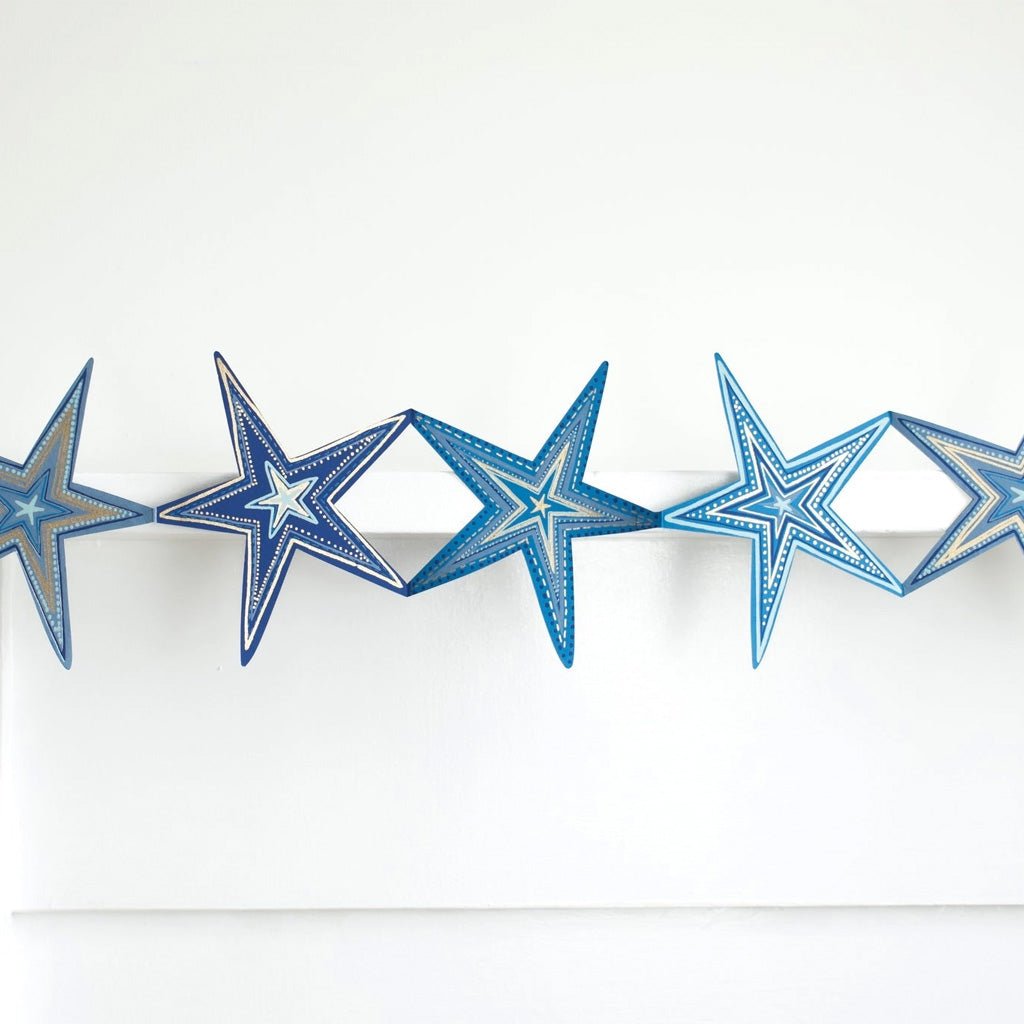 Blue star concertina garland hanging on white wall.
