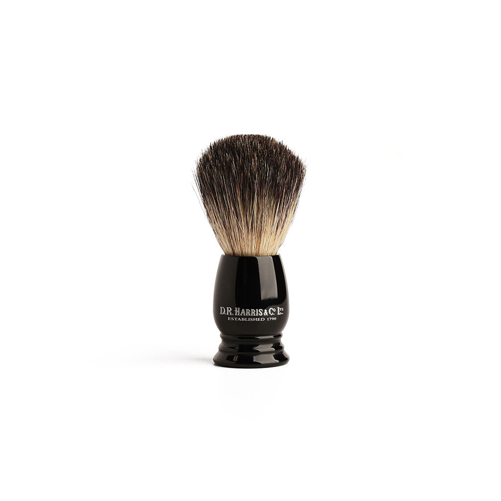 Shaving brush with black handle and badger bristles on a white background