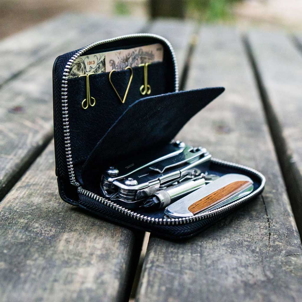 Open black wallet with tools on a wooden surface