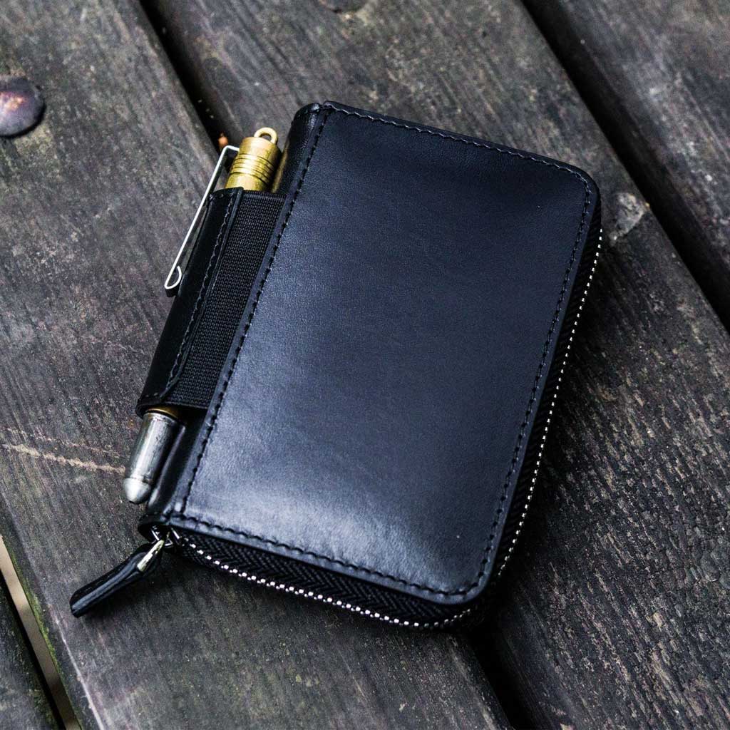 Black leather wallet with pen on a wooden surface