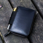 Black leather wallet with pen on a wooden surface