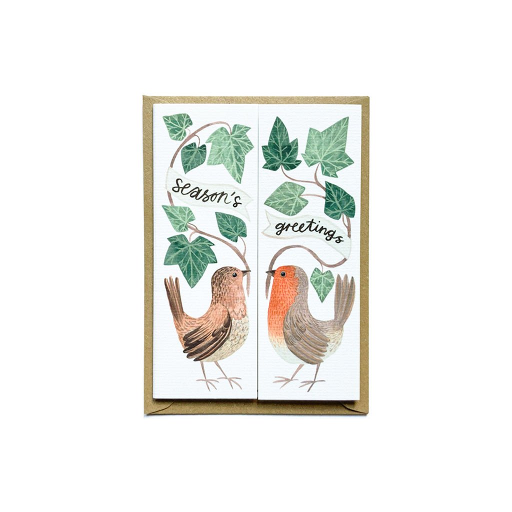 A closed card with illustrations and the message "Season's Greetings" in front of a kraft paper envelope.