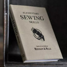 Book titled 'Elementary Sewing Skills' by Merchant & Mills on a dark background