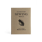 Book titled 'Elementary Sewing Skills' by Merchant & Mills on a beige background