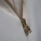 Close-up of a gold zipper on a white background