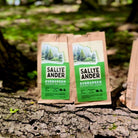 Two SallyeAnder evergreen essential soaps in packaging on tree trunk outside