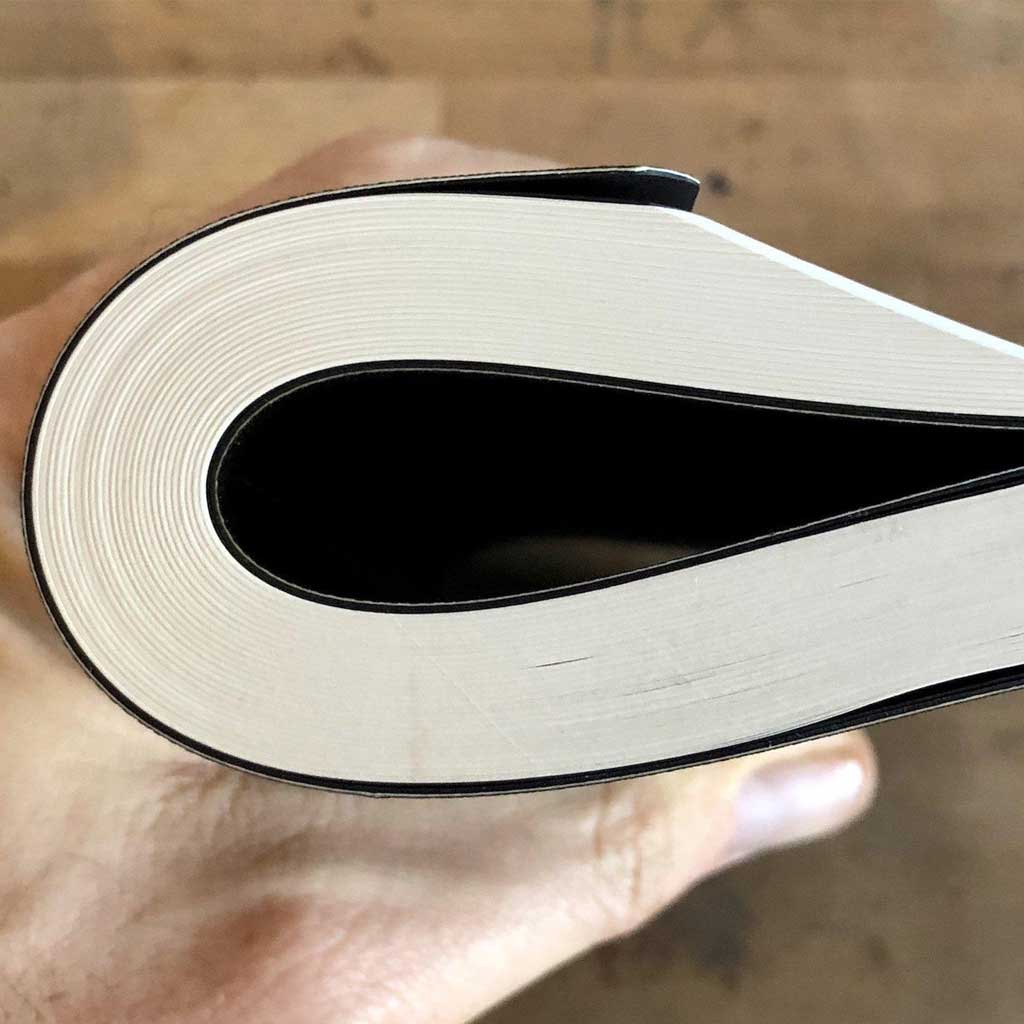 Close-up of a hand holding a softbook with a wooden surface in the background
