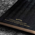 Black notebook with gold text on a textured surface