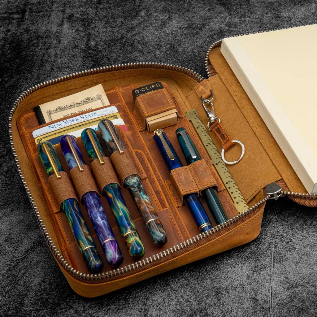 Leather case with pens, stationery items, and a notebook on a textured surface