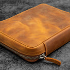 Brown leather zippered case on a dark textured surface