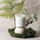 Fern + Moss candle with greenery on a neutral background
