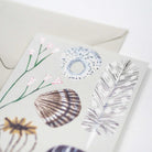 Greeting card with nature-themed design featuring a shell, flowers, and leaves on a white background.