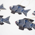 Set of five fish-shaped gift tags with colorful twine on white background