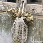 Net bag with dried flowers hanging on a rustic wooden door