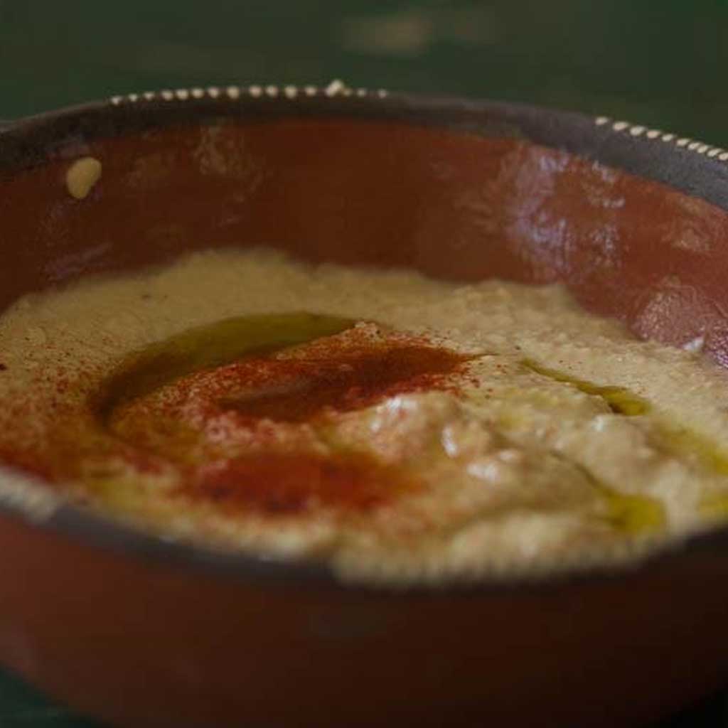 Close-up of a bowl with hummus on a dark background