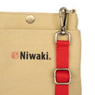 Beige canvas garden pouch with red strap and Niwaki branding on white background