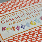 Origami kit packaging with colorful origami baubles and text on a white background