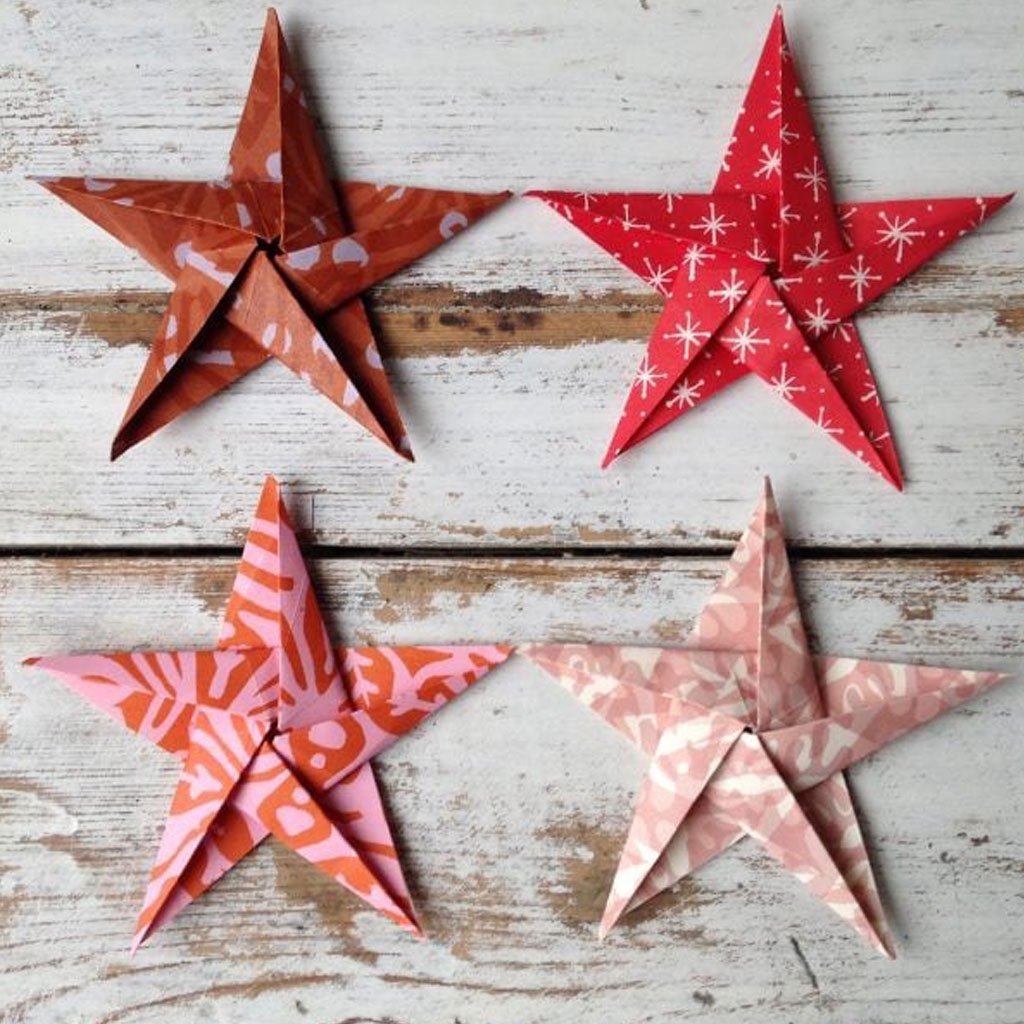 Four patterned paper stars on a wooden surface
