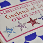 Close-up of an origami kit titled 'Garland of Stars' with star designs on the cover.