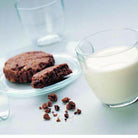 Chocolate cookies on a plate with a glass of milk on a white surface