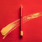 Red pen with gold accents on a red background with gold brush strokes
