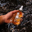 Hand holding a bottle with a dropper over water