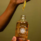 Bottle of 'Yay for Earth' Golden Body Oil with a dropper being used.
