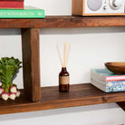 Wooden shelf with decorative items including a bottle, books, and a plant.