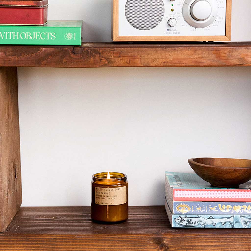 Candle on a wooden shelf with books and a radio in the background