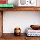 Candle on a wooden shelf with books and a radio in the background