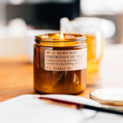 Lit P.F. Candle Co. candle in an amber jar on a wooden surface