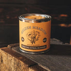 Candle in a tin labeled 'Golden Meadow' by Bradley Mountain on a wooden surface.