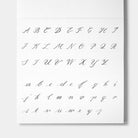 A white alphabet sheet showing uppercase and lowercase cursive script letters from A to Z in dark gray, photographed against a light gray background.
