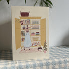 Holiday card standing upright on blue gingham fabric.