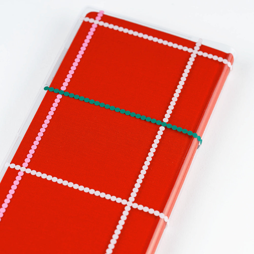 Clear Hobonichi Weeks clear cover with colorful dotted plaid pattern on red Weeks planner