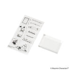 A clear acrylic stamp block next to a sheet of black-and-white cartoon-style Moomin stamp designs on a plain white background. 