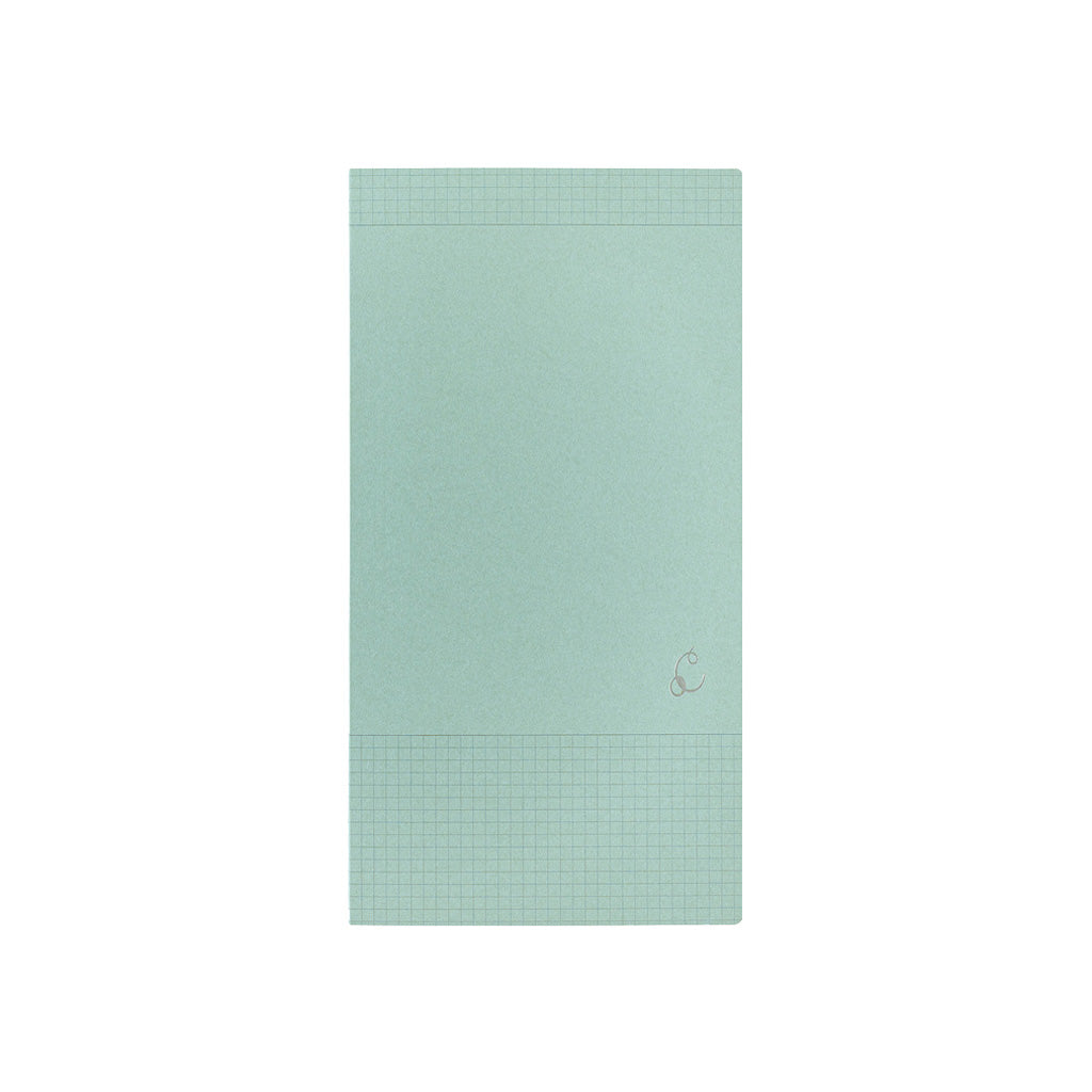 A mint green notebook with grid lines on the top and bottom borders, featuring a small silver monogram logo on the lower right, set against a plain white background.