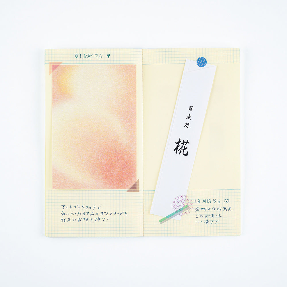 A pocket notebook with a cream-colored grid page, featuring a pastel peach watercolor illustration on the left, handwritten notes in Japanese, and a white bookmark with black calligraphy.