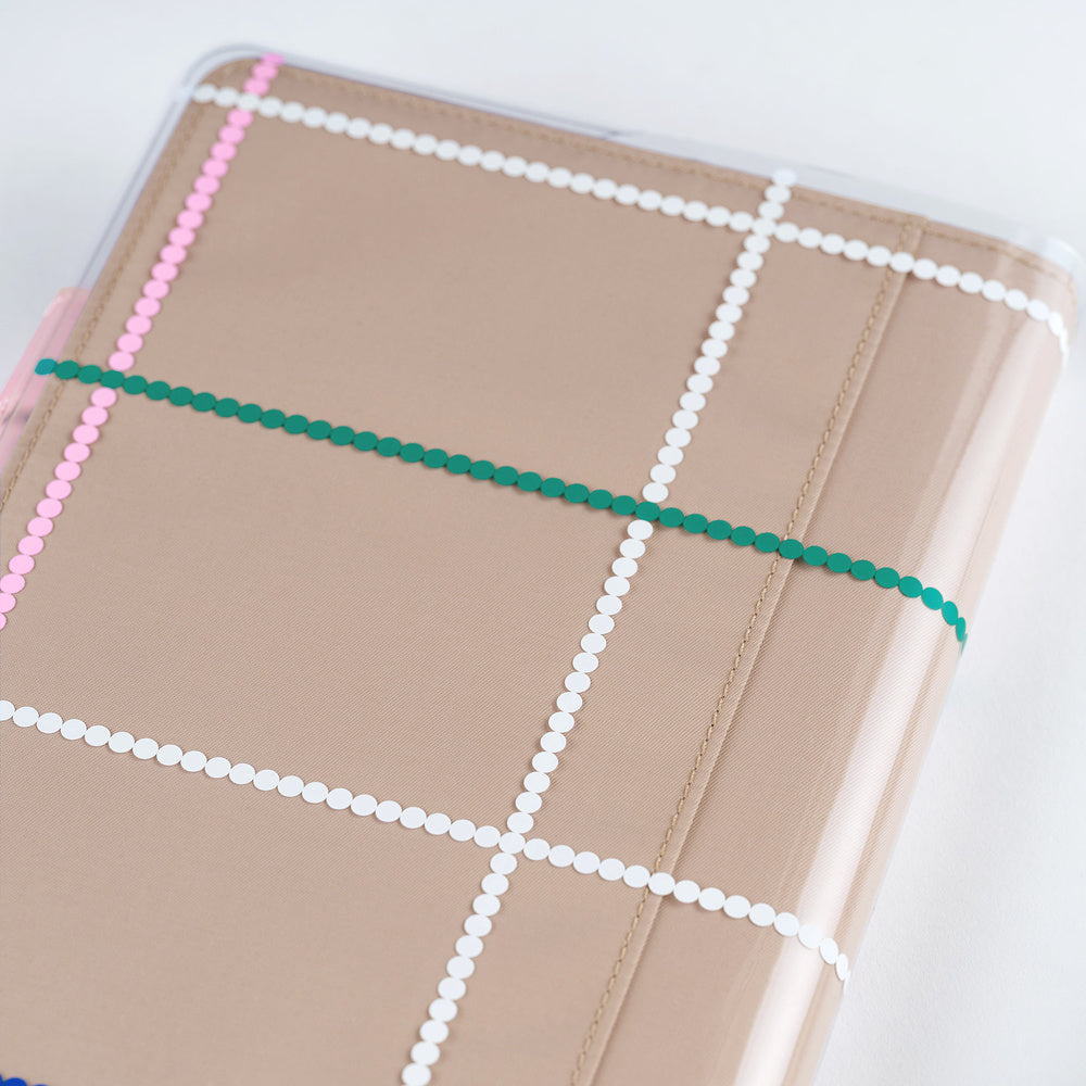 Clear cover on beige A5 Hobonichi Techo cover with colorful dotted plaid pattern against white background