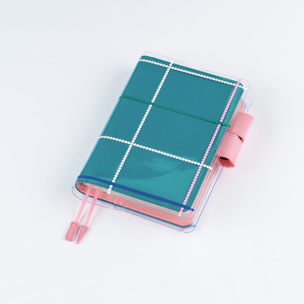 Clear cover on teal blue A6 Hobonichi Techo cover with colorful dotted plaid pattern against white background