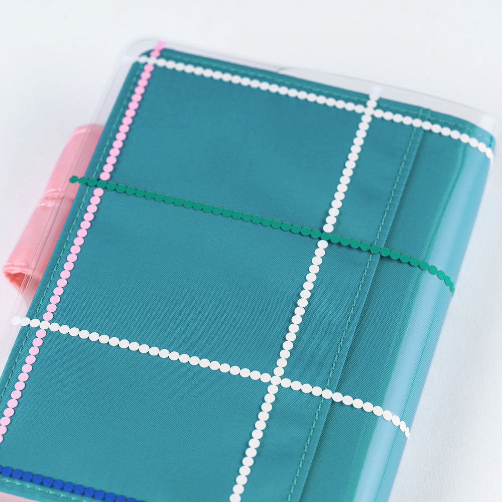Clear cover on teal blue A6 Hobonichi Techo cover with colorful dotted plaid pattern against white background