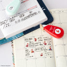 Calendar with Moomin character tape designs and a red Deco Rush tape dispenser on a grid background