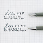 Two pens, one with a fountain pen nib and one with a Rollerball nib, shown on a white graph paper background with sample handwritten Japanese text and English transliterations.