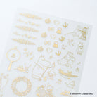 A sheet of transparent stickers featuring gold foil designs including Moomin characters, crowns, hearts, bows, and floral wreaths, displayed on a clean white background.