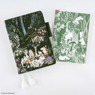 A5 notebook with Moomin dinner party scene design next to an A5 pencil board with green Moomin illustration against a white background