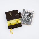 A dark planner with a yellow and black airport terminal cover design, shown next to its matching black-and-white pencil board on a clean white background.