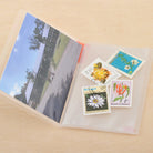 Collection of stamps with scenic and floral designs in a clear photo album case.